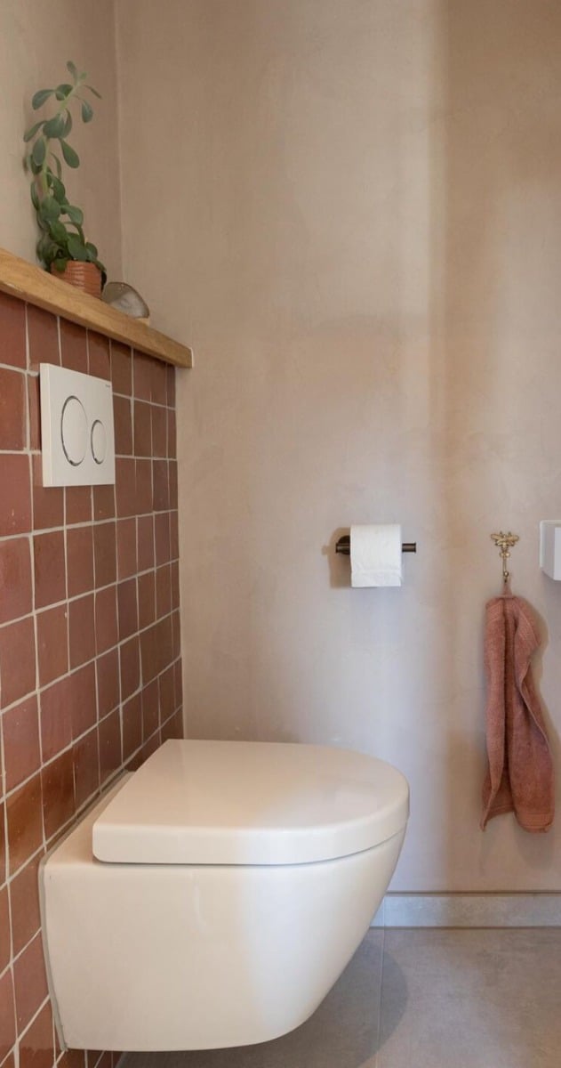 hangend toilet met roze accessoires en roze tegels
